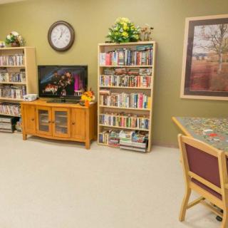 A cozy living room with bookshelves, a television, and a clock on the wall.