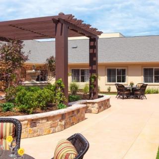A sunny courtyard with a pergola, garden, and outdoor seating.