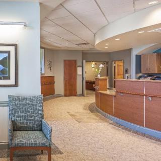 A modern hospital reception area with a curved desk and comfortable seating.