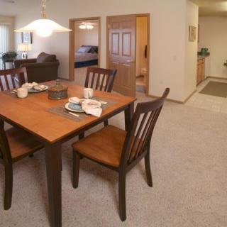 A cozy dining area with a wooden table and chairs, set in a carpeted room.