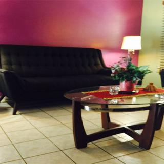 A cozy living room with a dark sofa, a stylish coffee table, and a warm lamp against a purple accent wall.
