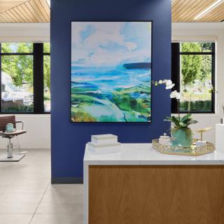 A modern reception area featuring a large abstract painting on a blue accent wall, with natural light streaming in through the large windows.