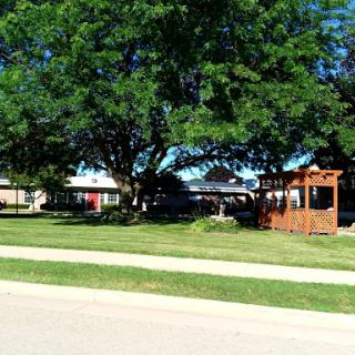 A peaceful suburban scene featuring a house surrounded by lush greenery and a charming gazebo.