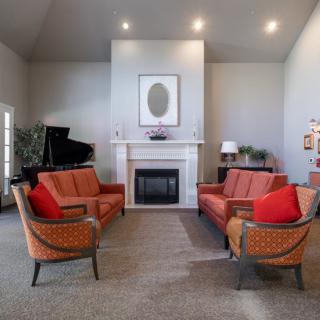 A modern living room featuring a grand piano and symmetrical seating arrangement around a fireplace.