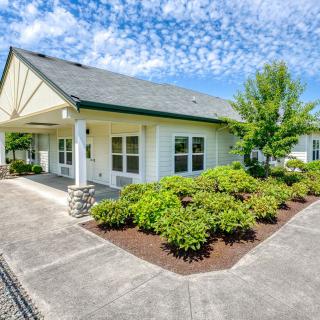 A well-maintained house with a landscaped garden and driveway under a blue sky with clouds.