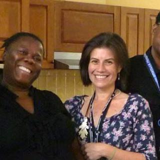 A group of people smiling together in a kitchen setting.
