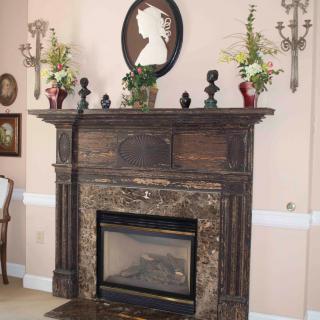 A vintage-style fireplace with a decorative mantelpiece adorned with flowers and silhouette art.
