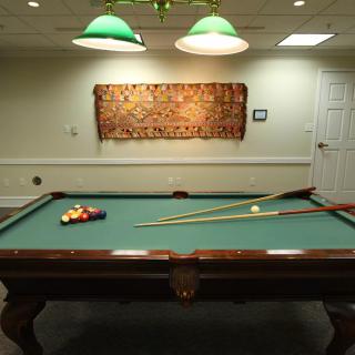 A billiards room featuring a pool table with cue sticks and balls ready for play.