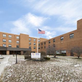 A brick apartment building with an American flag flying outside under a cloudy sky.