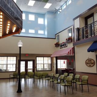 An interior space resembling a small town street, complete with decorative storefronts and seating.