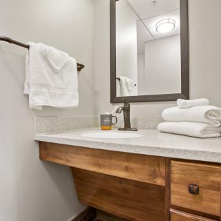 A clean and modern bathroom featuring a wooden countertop, towels, and a large mirror.