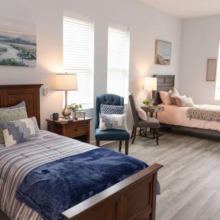 A modern bedroom featuring two twin beds, stylish decor, and wooden flooring.