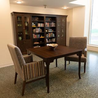 A cozy dining area featuring a wooden table and striped chairs, accompanied by a bookshelf filled with books.