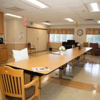 A spacious conference room with a long meeting table and chairs, decorated with flowers and well-lit by indoor lighting.