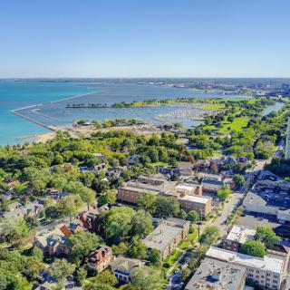 A scenic aerial view showcasing the lush green spaces adjacent to a tranquil lake and vibrant urban surroundings.