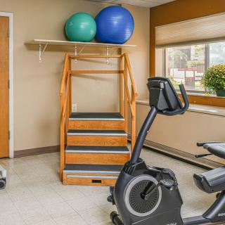 A home gym setup with a stationary bike, wooden staircase, and medicine balls.
