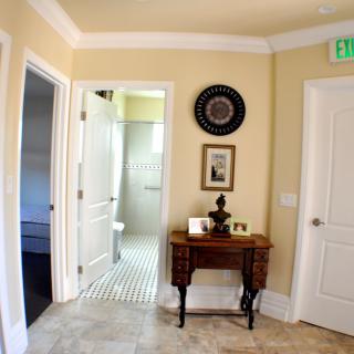 A hallway with a small table, decorative items, and access to a bathroom.