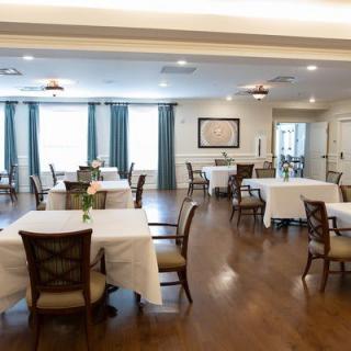 A spacious dining room with neatly arranged tables and chairs, featuring elegant decor and bright lighting.