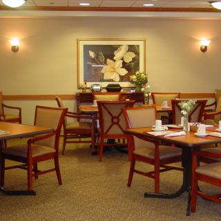 A cozy dining area with neatly set tables and chairs, complemented by elegant wall art.