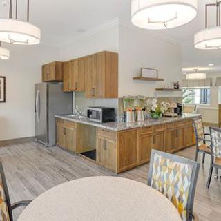 A modern kitchen with wooden cabinets, stainless steel appliances, and a dining area.
