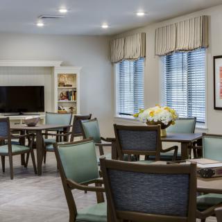 A cozy living area with multiple tables and chairs, a TV, and decorative elements.