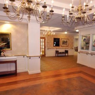 A spacious lobby area featuring elegant chandeliers, artwork, and a reception desk.