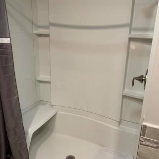A modern, clean white shower with built-in shelves and a seat.