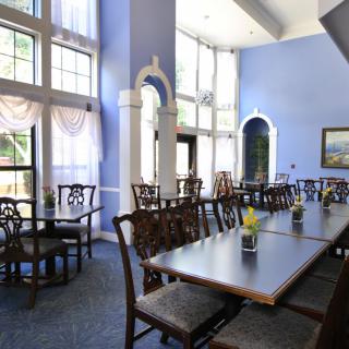 A spacious dining area with elegant tables and chairs, illuminated by large windows.