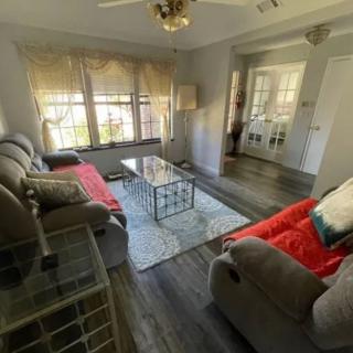 A cozy living room with comfortable sofas and a glass coffee table, illuminated by natural light from large windows.