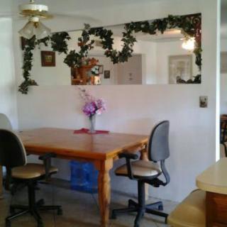 A cozy dining area with a wooden table, chairs, and decorative elements like a mirror and indoor plants.