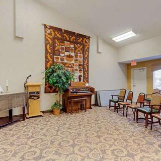 A cozy room with a piano, seating arrangements, and decorative elements including a tapestry and indoor plant.