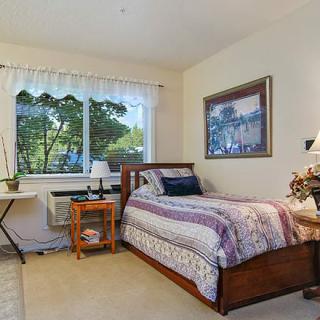 A cozy bedroom with a single bed, desk, and window view.