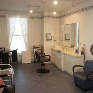 A well-lit hair salon interior featuring chairs and mirrors.