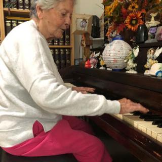 An elderly woman enjoying a moment of music at the piano.