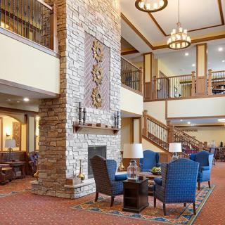 A spacious modern lobby featuring a stone fireplace, comfortable seating, and elegant chandeliers.