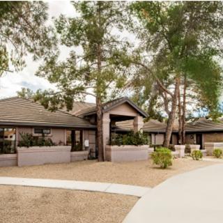 A suburban house surrounded by trees and landscaped walkways.