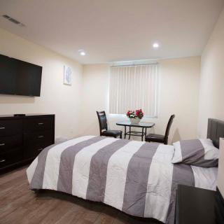 A modern bedroom with a striped bedding set, a wall-mounted television, and a small dining area.