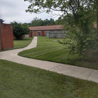 A serene view of a landscaped area featuring a winding pathway and well-manicured grass.