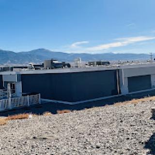 A modern building with a backdrop of mountains under a clear blue sky.