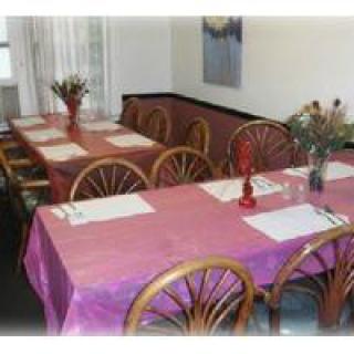 A cozy dining area with tables set for a meal, featuring floral decorations.