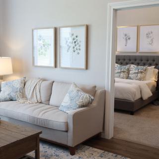 A cozy living room with a neutral-toned sofa and adjacent bedroom.