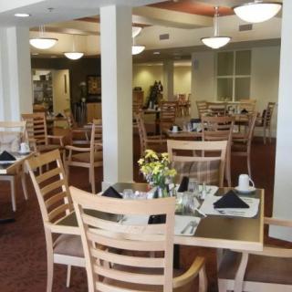An empty restaurant dining area with neatly set tables and chairs, featuring warm lighting and simple decor.