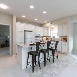 A modern kitchen with white cabinets and bar stools at the countertop.