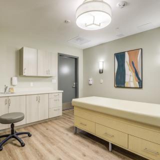 A modern medical examination room with an examination table and contemporary artwork on the wall.