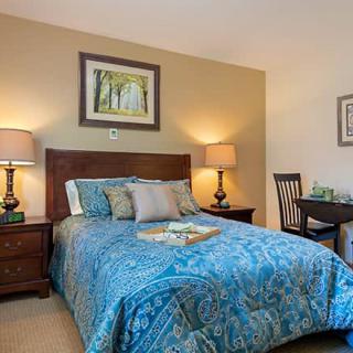 A cozy bedroom with a neatly made bed, bedside lamps, and decorative artwork.