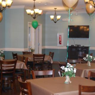 A decorated dining area with tables, chairs, and balloons.