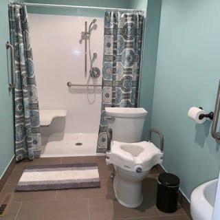 A modern, handicap-accessible bathroom featuring a shower with grab bars and a toilet with additional support.