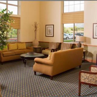 A comfortable lobby seating area with sofas and tables, featuring large windows and tasteful decor.