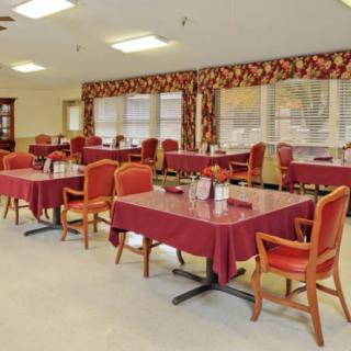 An empty dining room with red tablecloths and wooden chairs arranged neatly.