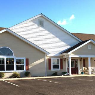 A suburban residential building with a peaked roof and large windows on a clear day.